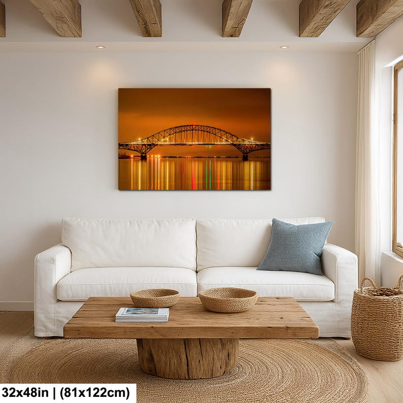 May include: A 32x48 inch (81x122cm) canvas print of a bridge at night. The bridge is illuminated with lights, reflecting in the water below. The sky is a warm orange color.