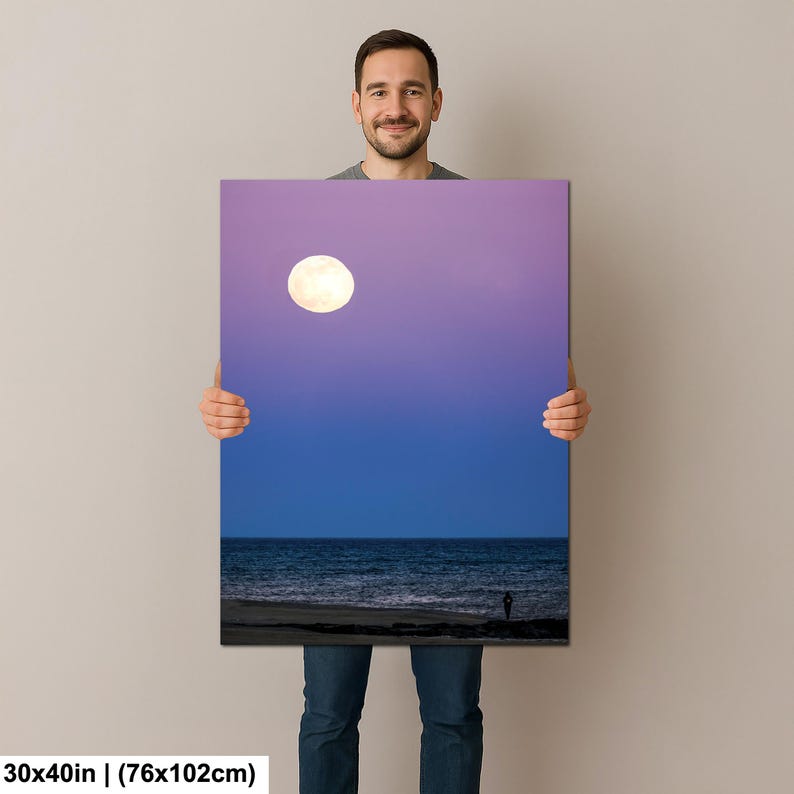 May include: A canvas print featuring a vibrant night scene. The artwork depicts a full moon in a gradient sky above a dark ocean and a silhouetted figure on the beach. The canvas measures 30x40 inches.