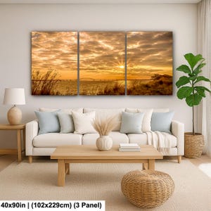 May include: A three-panel canvas print depicting a sunset over a body of water, with a bridge in the distance. The sky is filled with golden and orange hues, and the print measures 40x90 inches.