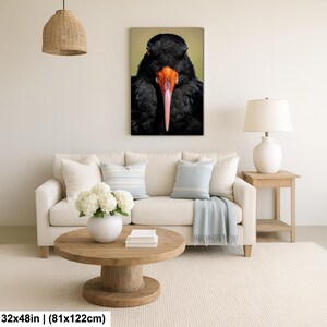 May include: A framed canvas print featuring a close-up of a black bird with a long, pink beak and orange accents. The bird's feathers are detailed, and the background is a soft, muted green. The print measures 32x48 inches.