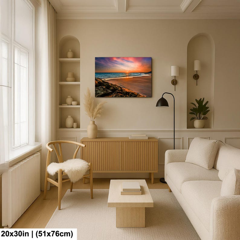 May include: A framed canvas print depicting a beach scene at sunset. The artwork showcases a vibrant sky with orange, pink, and blue hues, reflecting on the water. The print measures 20x30 inches.