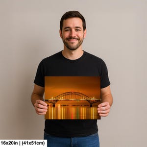 May include: A photograph of a bridge at night, with the lights reflecting in the water. The bridge is arched and has lights along its length. The photograph is 16x20 inches (41x51cm).