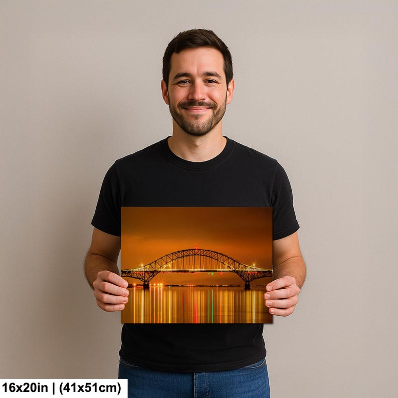May include: A photograph of a bridge at night, with the lights reflecting in the water. The bridge is arched and has lights along its length. The photograph is 16x20 inches (41x51cm).