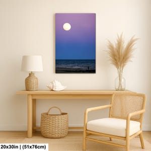 May include: A canvas print of a moonlit beach scene. The artwork features a full moon in a purple and blue sky, with a dark ocean and a silhouetted figure on the shore. The print measures 20x30 inches.