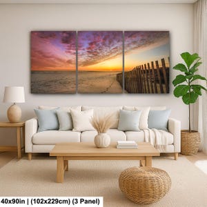 Peut inclure: Impression sur toile en trois panneaux repr&eacute;sentant une sc&egrave;ne de plage au coucher du soleil. Le ciel est rempli de teintes roses, violettes et orang&eacute;es. Une cl&ocirc;ture en bois longe la plage. Dimensions : 102x229cm.