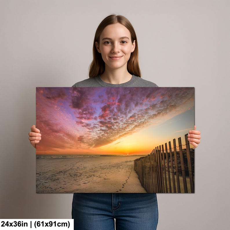 Peut inclure: Impression sur toile d'une sc&egrave;ne de plage au coucher du soleil. Le ciel est rempli de couleurs vives d'orange, de rose et de violet. Une cl&ocirc;ture en bois longe le c&ocirc;t&eacute; droit de la plage. L'impression mesure 61x91cm.