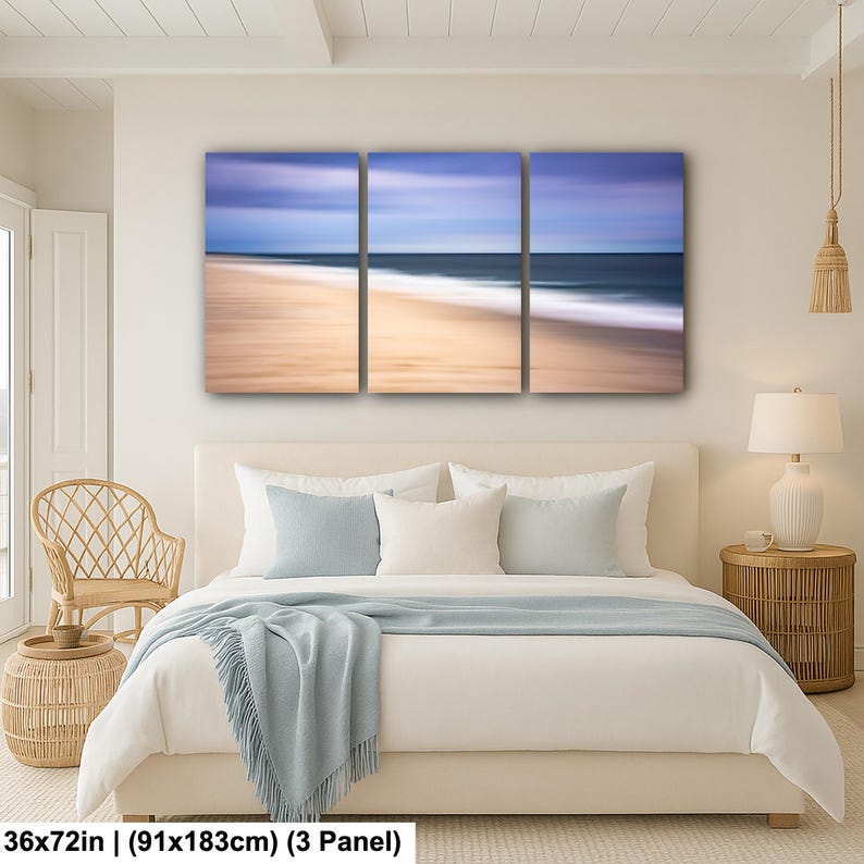 May include: A triptych canvas print depicting a coastal scene. The artwork features a blurred effect of the ocean, beach, and sky, with colors of blue, beige, and white. The dimensions are 36x72 inches.