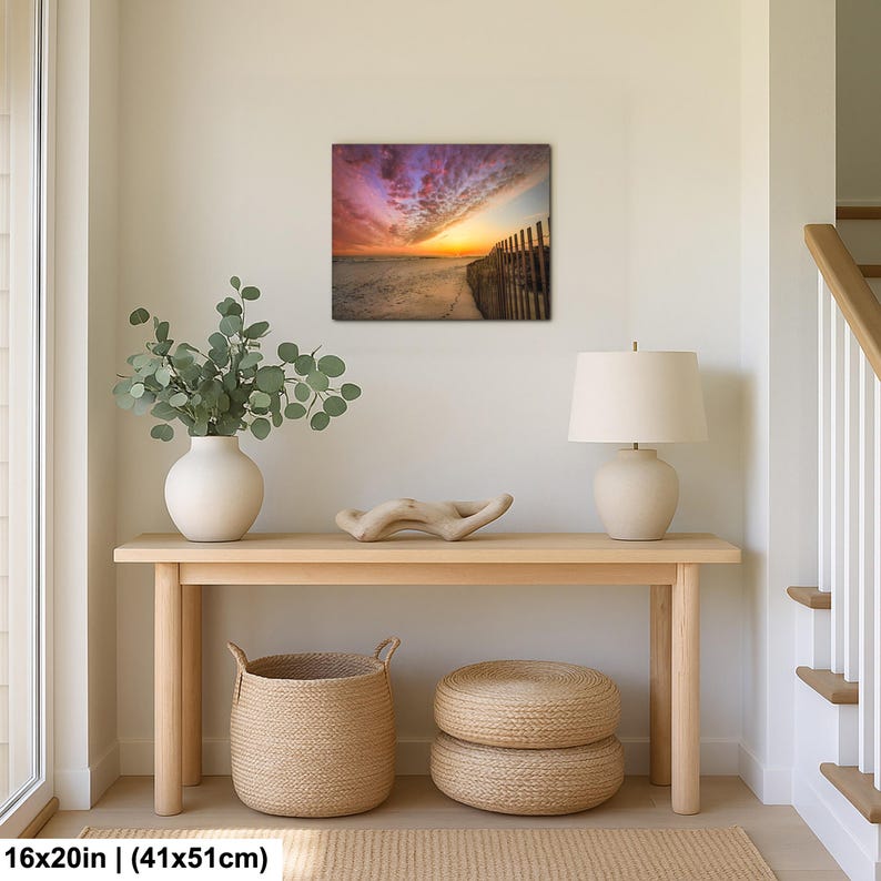 Peut inclure: Tableau encadr&eacute; de 41x51cm repr&eacute;sentant une sc&egrave;ne de plage au coucher du soleil. L'&oelig;uvre pr&eacute;sente un ciel color&eacute;, une plage de sable et une cl&ocirc;ture en bois. Le tableau est expos&eacute; au-dessus d'une console en bois.