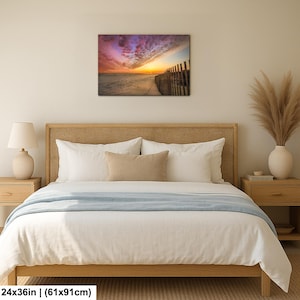 Peut inclure: Impression sur toile encadr&eacute;e d'un coucher de soleil vibrant sur une plage, avec des nuances de violet, d'orange et de jaune dans le ciel. L'&oelig;uvre mesure 61x91cm et pr&eacute;sente une cl&ocirc;ture en bois le long du rivage.