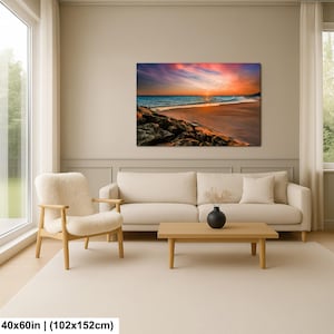 May include: A large canvas print of a beach scene at sunset. The sky is filled with vibrant colors of pink, orange, and blue. The ocean waves gently roll onto the sandy shore. The print measures 40x60 inches.