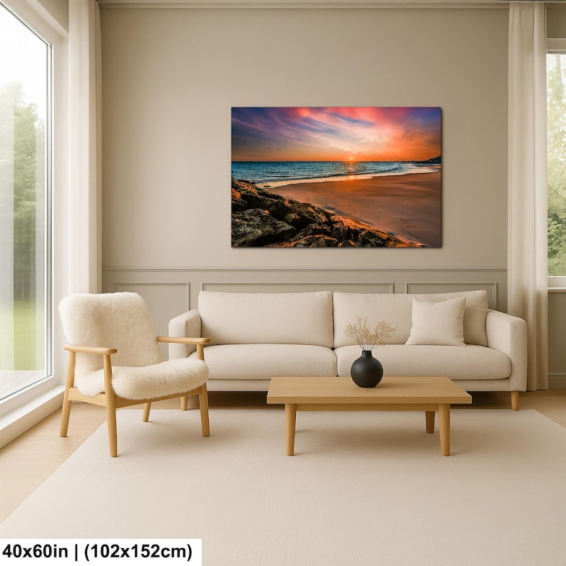May include: A large canvas print of a beach scene at sunset. The sky is filled with vibrant colors of pink, orange, and blue. The ocean waves gently roll onto the sandy shore. The print measures 40x60 inches.