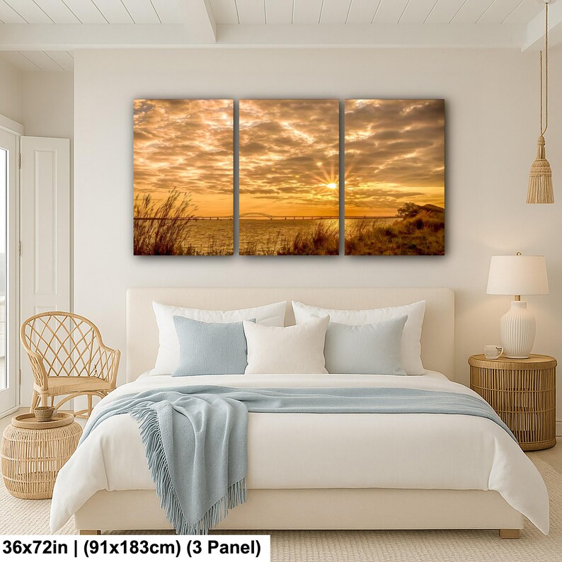 May include: A three-panel canvas print depicting a sunset over water. The sky is filled with golden clouds, and the sun's rays burst through. The print measures 36x72 inches.