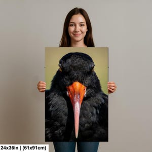 May include: A close-up photograph of a black bird with a long, bright orange beak. The bird's feathers are a deep black, and its eyes are visible. The background is a soft green and tan. The dimensions of the print are 24x36 inches.