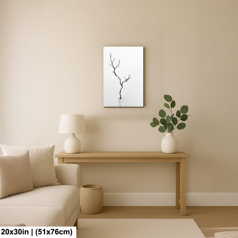 May include: A framed art print featuring a minimalist black and white image of a tree branch. The artwork is displayed on a wall above a wooden console table. The print measures 20x30 inches.