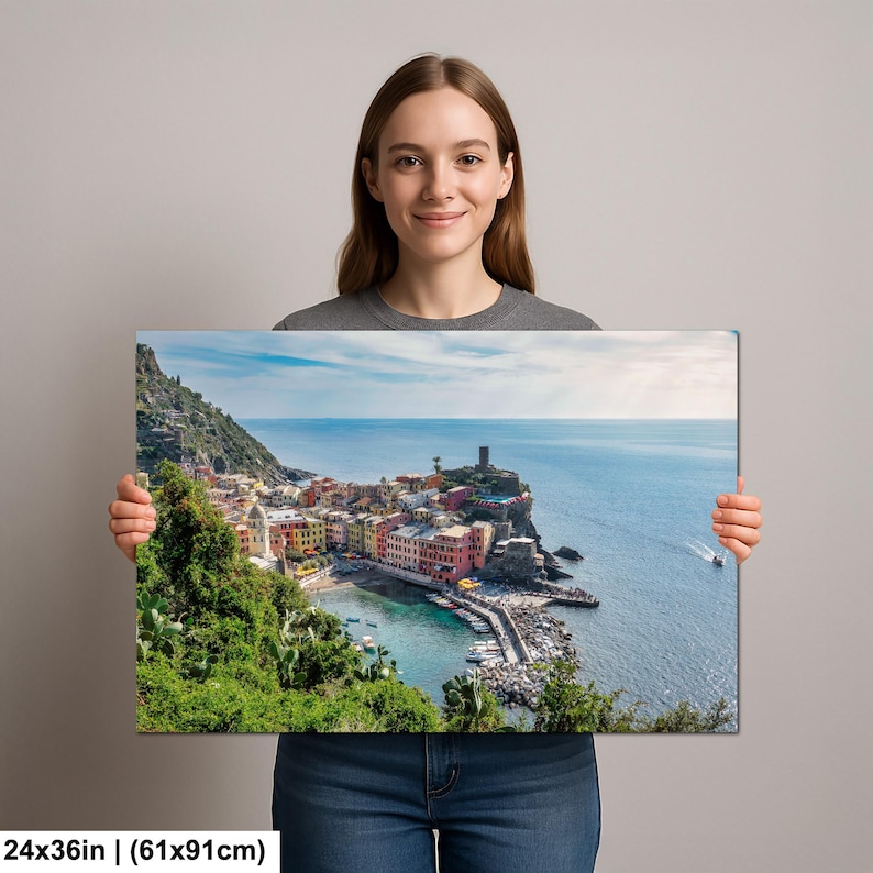 May include: A canvas print featuring a coastal town with colorful buildings, a harbor, and a tower on a cliff. The print measures 24x36 inches (61x91cm). The scene is set under a blue sky with a few clouds, and the sea is visible.