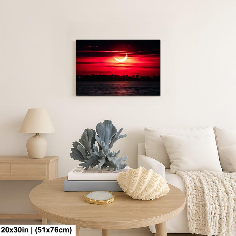 Pode incluir: Impress&atilde;o em tela emoldurada retratando um eclipse solar sobre a &aacute;gua. O c&eacute;u &eacute; vermelho vibrante com um sol em forma de crescente. A impress&atilde;o mede 51 cm x 76 cm.