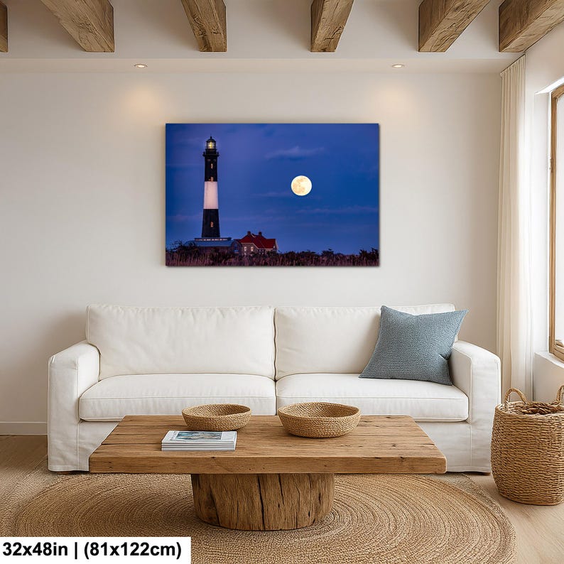 May include: A canvas print of a lighthouse under a full moon. The lighthouse is black and white with a red-roofed building nearby. The moon is bright yellow against a dark blue sky. The print measures 32x48 inches.