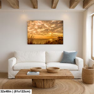 May include: A large rectangular canvas print depicting a sunset over a body of water. The sky is filled with golden clouds, and the sun's rays burst through. The print measures 32x48 inches (81x122cm).