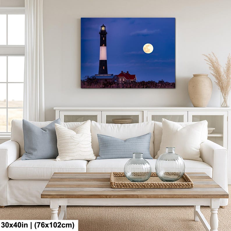 May include: A canvas print of a lighthouse under a full moon. The lighthouse is black and white with a red roofed building next to it. The print is 30x40 inches.