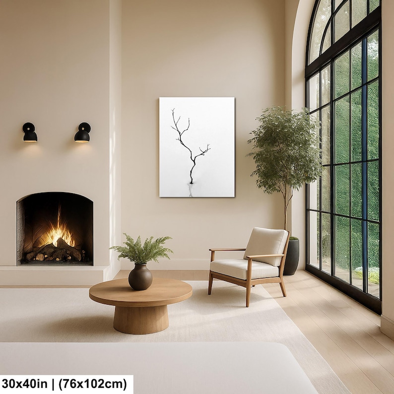 May include: A minimalist interior scene featuring a framed black and white art piece depicting a bare tree. The artwork is 30x40 inches (76x102cm). The room includes a fireplace, a round wooden coffee table, and a modern armchair.