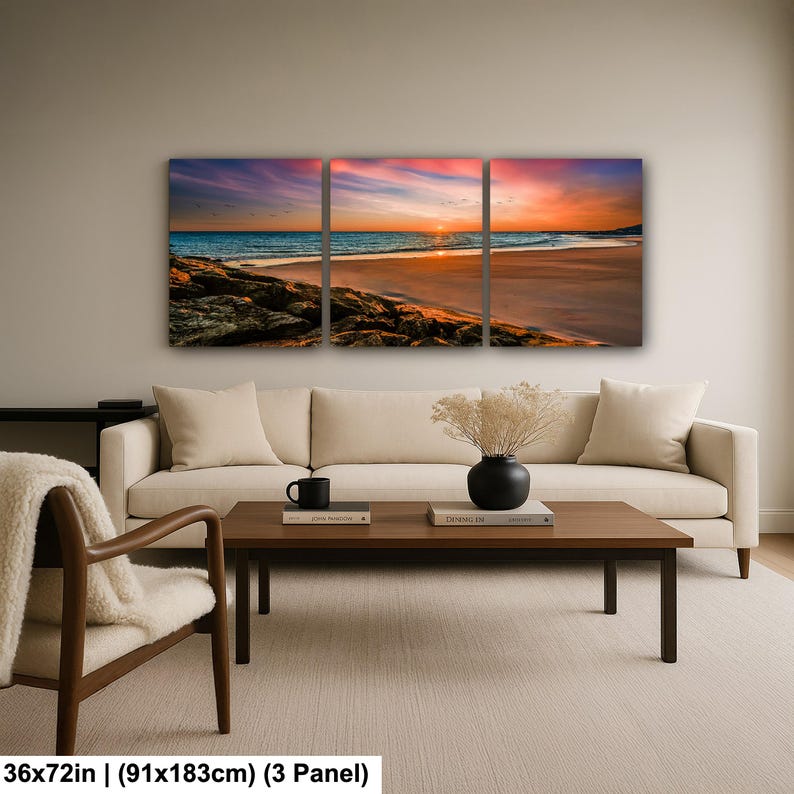 May include: A three-panel canvas print depicting a beach scene at sunset. The sky is a blend of orange, pink, and purple hues, reflecting on the water. The print measures 36x72 inches (91x183cm).