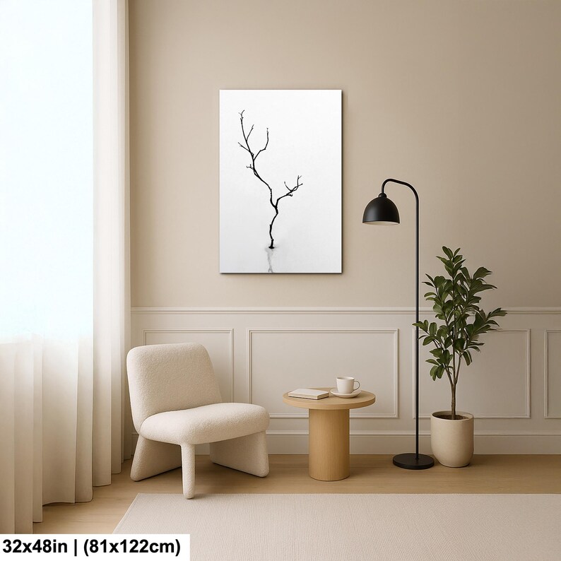 May include: A black and white minimalist art print featuring a bare tree silhouette. The artwork is rectangular, measuring 32x48 inches (81x122cm), and hangs on a neutral-toned wall. The room includes a chair, side table, floor lamp, and potted plant.