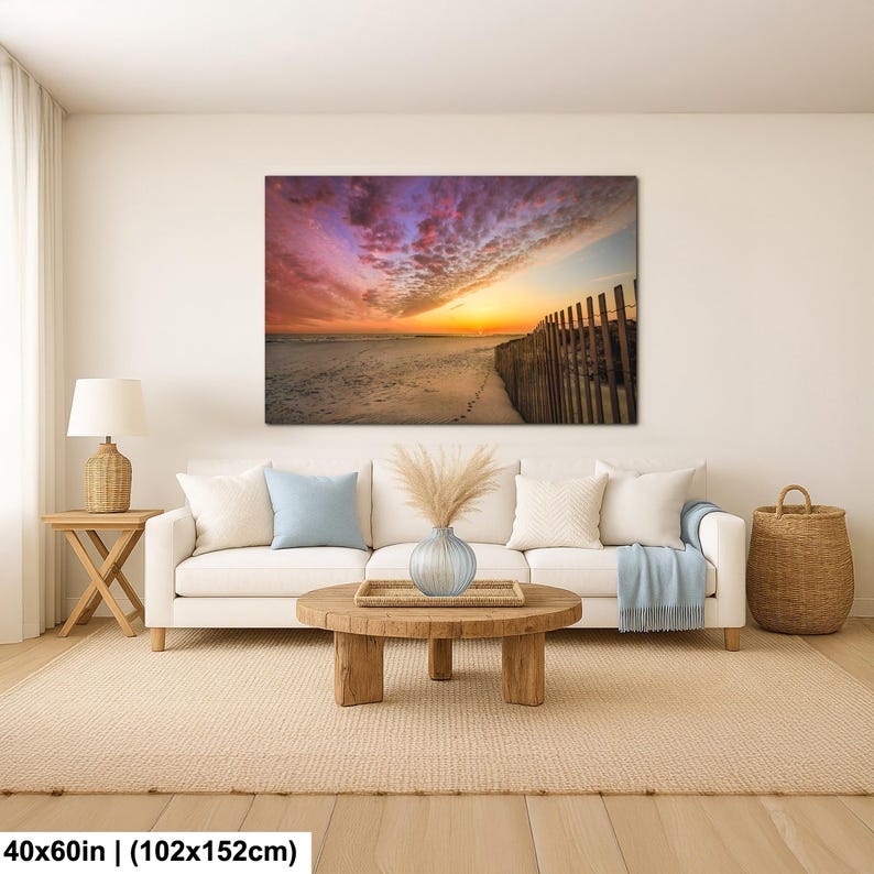 Peut inclure: Impression sur toile d'une sc&egrave;ne de plage au coucher du soleil. Le ciel est rempli de couleurs vives de rose, de violet et d'orange. Une cl&ocirc;ture en bois longe la plage. La toile mesure 102x152cm.