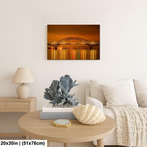 May include: A canvas print of a bridge at night, with the bridge's lights reflected in the water below. The print measures 20x30 inches.