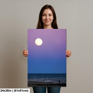 May include: A vertical canvas print featuring a full moon in a purple and blue sky over the ocean. The print measures 24x36 inches.