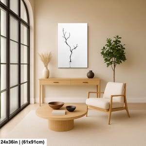 May include: A minimalist black and white canvas art print featuring a bare tree silhouette. The artwork is displayed in a modern living room setting, complemented by neutral-toned furniture and decor. The print measures 24x36 inches.