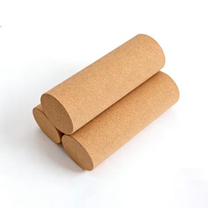 Può includere: Tre rulli cilindrici di sughero sono impilati su uno sfondo bianco. I rulli sono di colore marrone chiaro e hanno una superficie strutturata. Le estremità dei rulli sono di forma ovale.