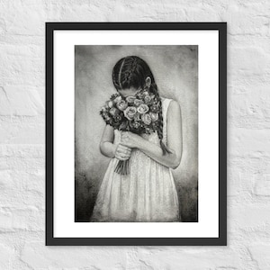Puede incluir: Impresión enmarcada en blanco y negro de una persona sosteniendo un ramo de flores. La persona lleva un vestido blanco y tiene el pelo largo. La obra de arte se exhibe en una pared de ladrillos blancos.