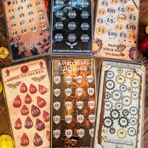 May include: A selection of scratch cards with different themes and text, such as "Purge and Save" and "Battle Fund Challenge." The cards display amounts in British pounds and are designed with a fantasy aesthetic.