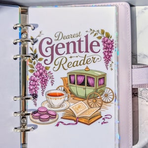 May include: A planner insert with a decorative design featuring the text "Dearest Gentle Reader." The illustration includes a green carriage, teacup, macarons, and an open book. The insert is in a light purple planner.