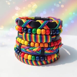 May include: A collection of rainbow-coloured bracelets. The bracelets are made with braided threads, beads, and leather. The bracelets are stacked, creating a vibrant display of colours. The bracelets are suitable for a variety of wrist sizes.