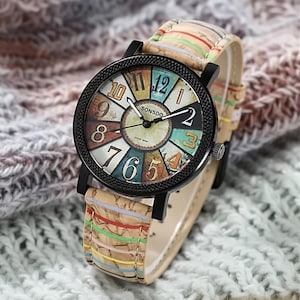 May include: A wristwatch with a black bezel and a colorful face featuring the text "SONSDO". The watch has a beige band with colorful stripes. The watch face displays the numbers 1 through 12.