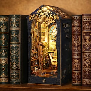May include: A decorative bookshelf with a miniature library scene inside, illuminated by a warm light. The bookshelf is flanked by several antique books with ornate gold detailing and various colors, including burgundy, green, and tan.