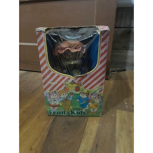 May include: A white ceramic mug with a black handle and the text "But First, Coffee" in a black, handwritten-style font. The mug is on a white surface.