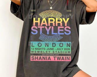 May include: A charcoal gray t-shirt featuring a colorful graphic print that reads TOGETHER HARRY STYLES TOGETHER LONDON 12 NIGHTS JUNE - JULY 2026 WEMBLEY STADIUM WITH VERY SPECIAL GUEST SHANIA TWAIN. The design uses a rainbow gradient color scheme.