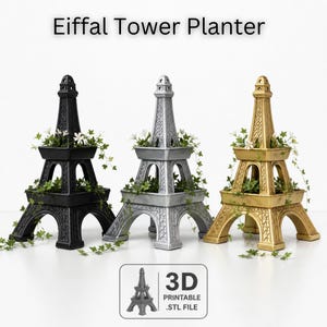 Könnte beinhalten: Drei Eiffelturm-Pflanzgefäße in Schwarz, Silber und Gold, jeweils mit Grün und weißen Blumen. Die Pflanzgefäße haben eine rechteckige Basis und ein detailliertes Turmdesign. Der Text "Eiffel Tower Planter" ist enthalten.