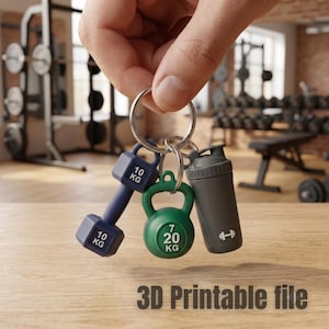 May include: A metal keyring featuring three miniature gym-themed charms: a navy blue dumbbell labeled 10 KG, a green kettlebell labeled 7 20 KG, and a grey protein shaker bottle with a white dumbbell icon. The text 3D Printable file is visible.
