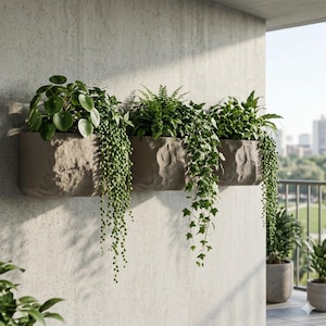 Pode incluir: Uma floreira retangular, texturizada, cor de pedra, montada numa parede de betão, preenchida com várias plantas verdes. As plantas pendentes caem em cascata, criando uma exibição natural e decorativa. A cena é num varanda com vista para a cidade.