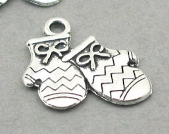 May include: Two silver charm pendants shaped like mittens with a chevron pattern. Each mitten has a small bow on the top.