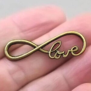 May include: A gold-toned infinity symbol charm with the word "love" inscribed on it.