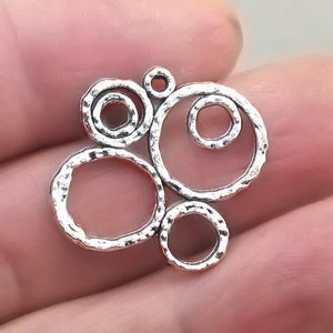 May include: Silver charm with a textured surface and a design of overlapping circles.