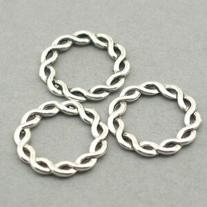 May include: Three silver braided rings, each with a circular shape. The rings are made of twisted metal wire.