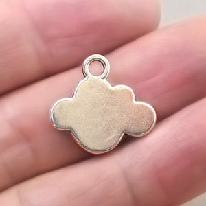 May include: A silver-colored cloud charm with a loop at the top for attaching to jewelry. The charm has a smooth, rounded shape, and is likely made of metal. This charm is suitable for necklaces, bracelets, or earrings.