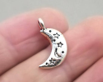 May include: Silver crescent moon charm with a star design. The charm has a loop at the top for attaching to jewellery.