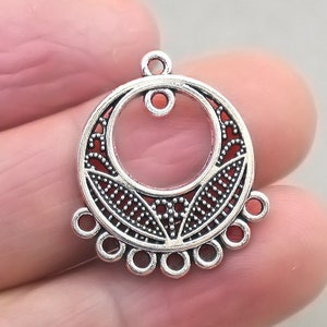 May include: Silver filigree circle pendant with a smaller circle in the centre and a row of small circles around the bottom edge.
