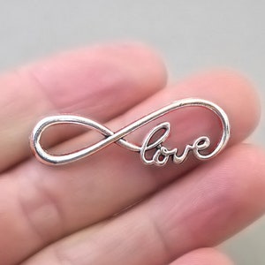May include: Silver infinity symbol charm with the word "love" inscribed on it.